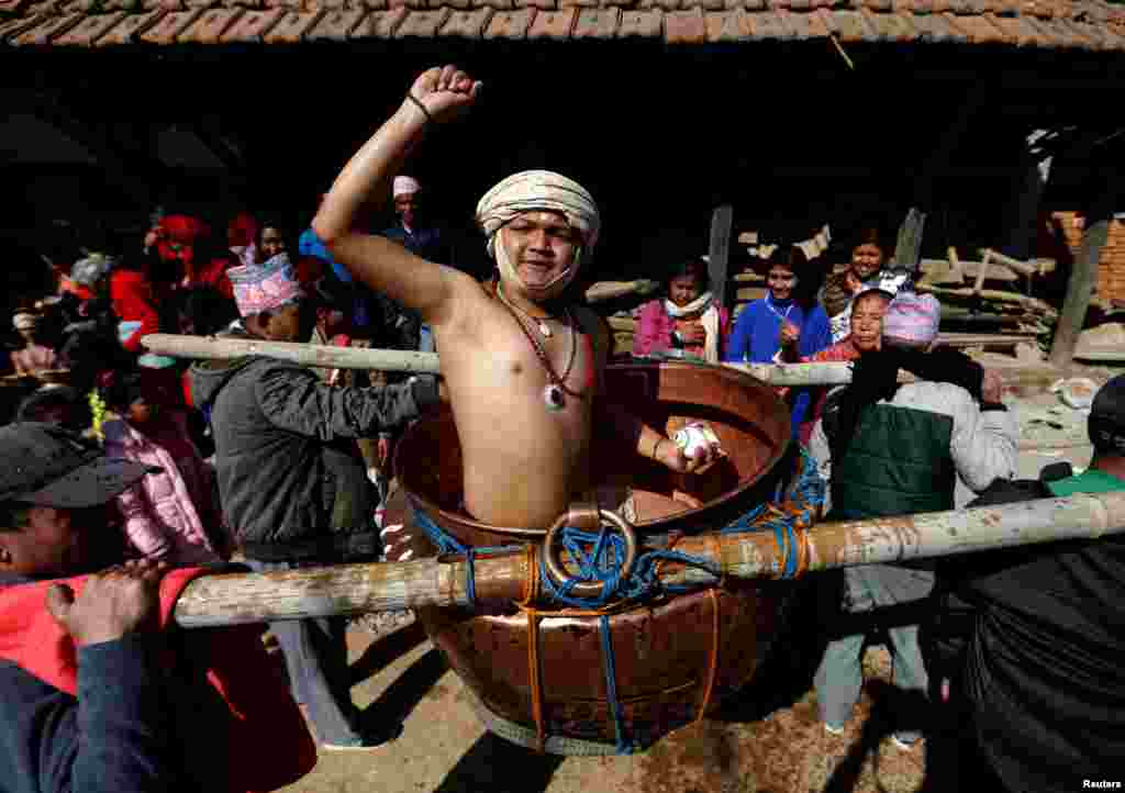 A devotee sprinkles water, considered holy, while being carried around the town in a vessel as part of rituals during the Swasthani Brata Katha festival in Thecho, Lalitpur, Nepal.