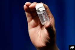 FILE - A reporter holds up an example of the amount of fentanyl that can be deadly after a news conference about deaths from fentanyl exposure, at DEA headquarters in Arlington, Va., June 6, 2017.