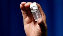 FILE - A reporter holds up an example of the amount of fentanyl that can be deadly after a news conference about deaths from fentanyl exposure, at DEA headquarters in Arlington, Va., June 6, 2017.