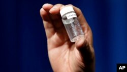 FILE - A reporter holds up an example of the amount of fentanyl that can be deadly after a news conference about deaths from fentanyl exposure, at DEA headquarters in Arlington, Virginia, June 6, 2017.