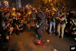 FILE - A black-clad protester wearing goggles and a mask stomps on a burning Chinese flag in Hong Kong, Saturday, Sept. 28, 2019.