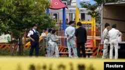 Workers of Tokyo's Toshima ward office and police officers are seen in front of the playground equipment where high levels of radiation were detected at a park in Toshima ward, Tokyo, April 24, 2015. 