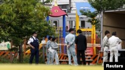 Pekerja distrik Toshima Tokyo dan petugas polisi dekat taman bermain di mana terdeteksi radiasi. Distrik Toshima, Tokyo. 