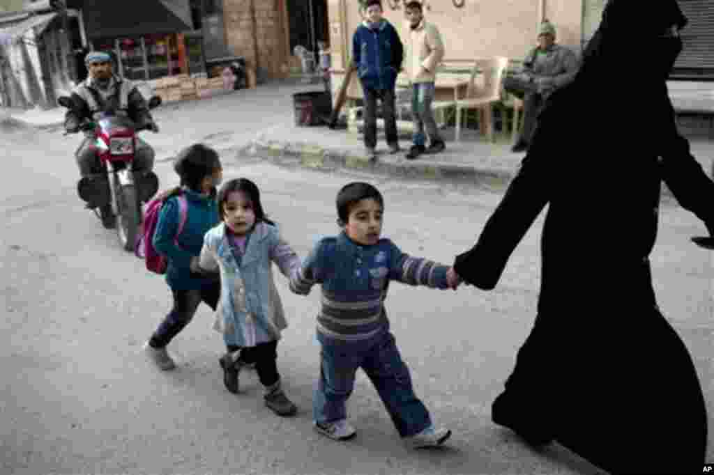 A woman walks with children in Kafar Taharim, north Syria, Saturday, Feb. 25, 2012.