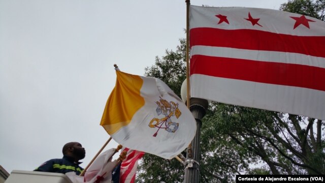 Un trabajador municipal coloca banderas del Vaticano, EE.UU. y el Distrito de Columbia en la avenida Pennsylvania por donde pasará la caravana papal.