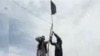 FILE - Members of Islamic State-Khorasan raise a flag in a tribal region of Afghanistan, Nov. 2, 2015.