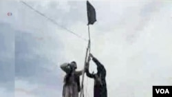 FILE - IS-Khorasan group members mount a flag in a tribal region of Afghanistan, Nov. 2, 2015. 