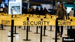 FILE - Passengers make their way in a security checkpoint at the International JFK airport in New York.