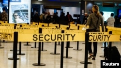 FILE - Passengers make their way in a security checkpoint at the International JFK airport in New York.