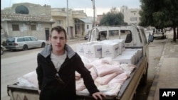FILE - This undated photo shows Peter Kassig leaning against a truck at an unknown location.