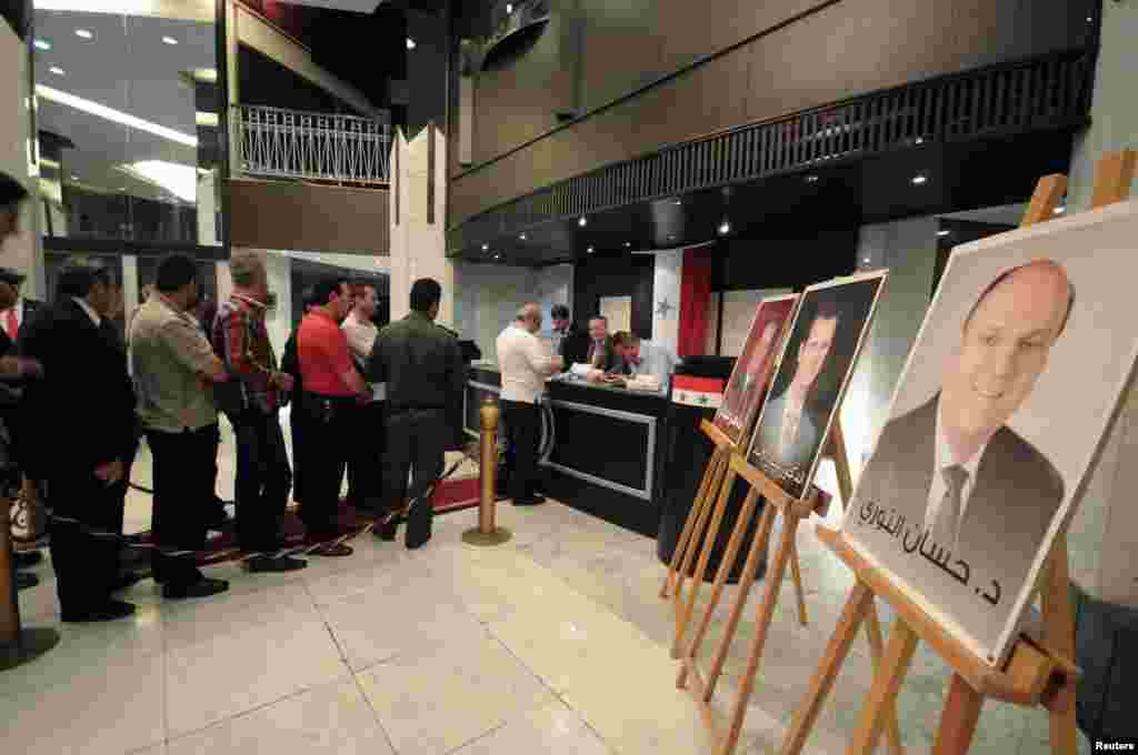 People line up to cast their votes in the presidential election near portraits of the candidates at the Dama Rose hotel in Damascus, June 3, 2014.