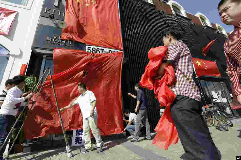 Workers at a Japanese restaurant cover up the shop front with Chinese national flags and red clothes ahead of major protests expected on Tuesday in Beijing, China, September 17, 2012.