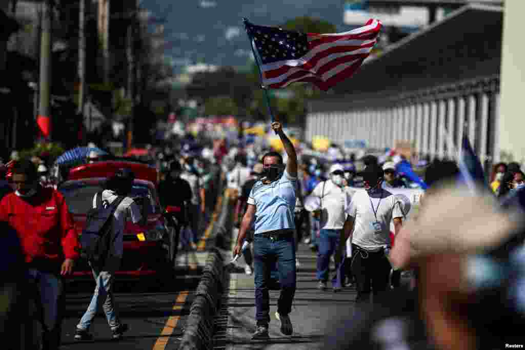 Un hombre agita una bandera estadounidense durante una protesta contra las acciones del Gobierno del presidente de El Salvador, Nayib Bukele.