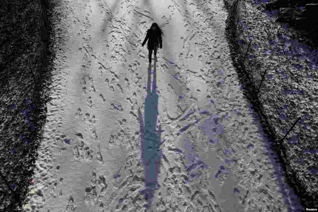 A woman walks in a snow covered path at Central Park in New York.