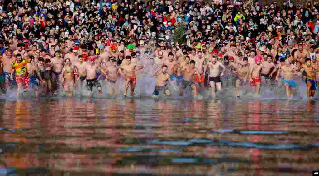Para perenang berlari ke air Danau Balaton yang dingin membeku, dalam acara berenang tahunan pada Tahun Baru di Szigliget, barat daya Budapest, Hongaria.