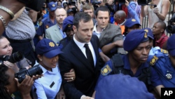 Escoltado por la policía Oscar Pistorius abandona la corte en Pretoria luego de escuchar los cargos por la muerte de su novia.