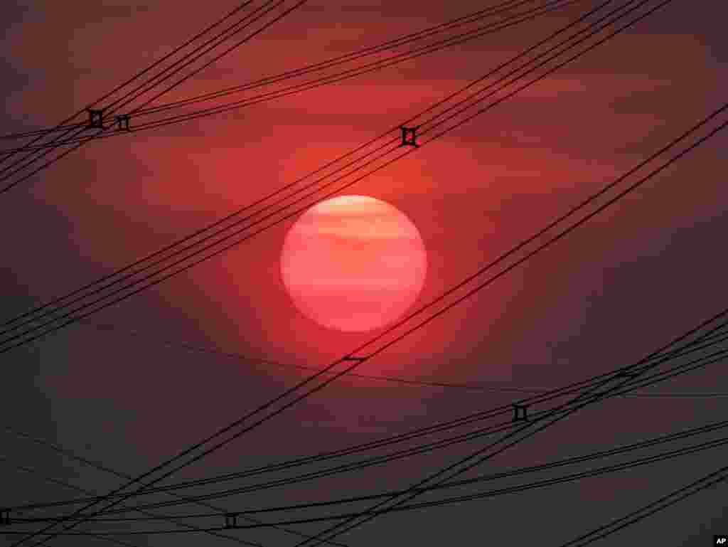 The sun rises between power lines in Frankfurt, Germany.