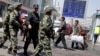 FILE - Armed Chinese paramilitary policemen march past the site of an explosion outside the Urumqi South Railway Station in Urumqi in northwest China's Xinjiang Uygur Autonomous Region, May 1, 2014.