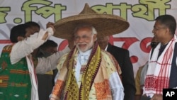India's main opposition Bharatiya Janata Party's prime ministerial candidate Narendra Modi is presented with a traditional hat during an election campaign rally at Gogamukh, in the northeastern state of Assam, India, Monday, March 31, 2014.