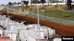 Trucks wait in a long queue at border customs control to cross into the U.S, at the Otay border crossing in Tijuana, Mexico, April 3, 2019. The wait has been caused by the redeployment of border officers to deal with a surge in migrants. 