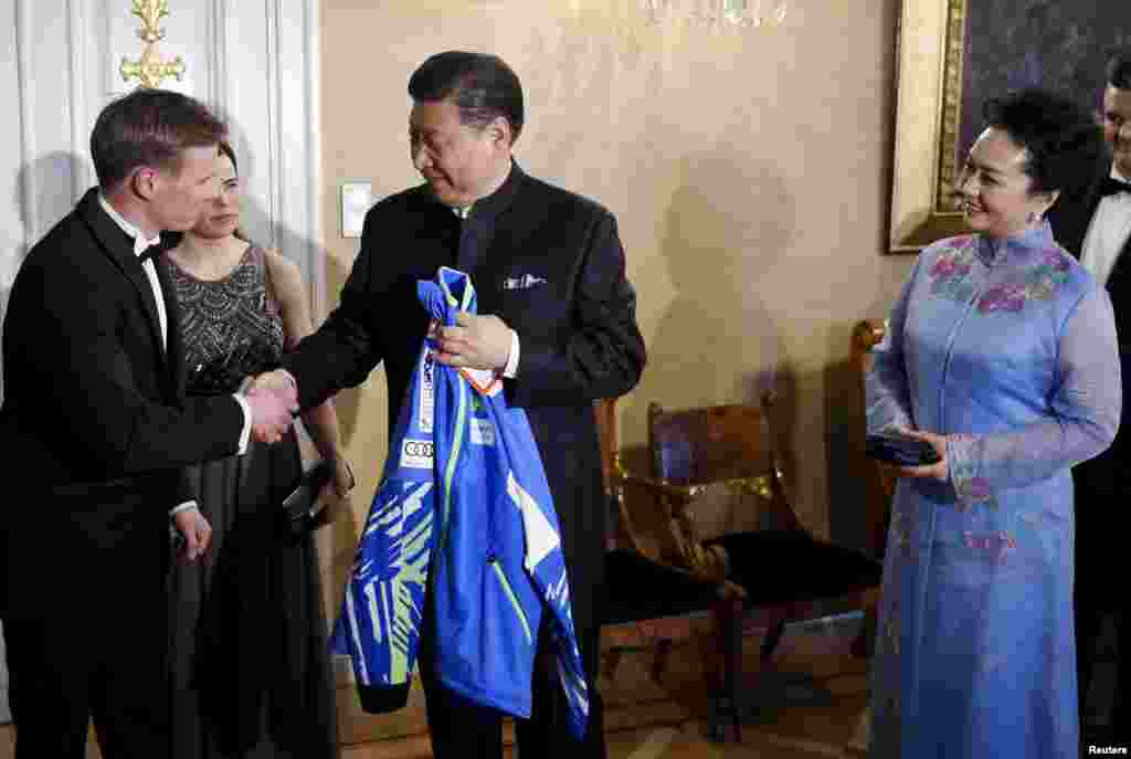 中國主席習近平和夫人在芬蘭赫爾辛基參加國宴前，接受芬蘭國家滑雪隊贈送的運動衣（2017年4月5日）。習近平夫婦從芬蘭來到美國。有評論人士認為，這是要顯示習近平並非專程訪美，而是順道訪美。