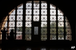 FILE - Tourists photograph the Statue of Liberty from the Registry Room at Ellis Island, July 29, 2015, in New York. Ellis Island processed more than 12 million immigrants during its operation from 1892 through 1954.