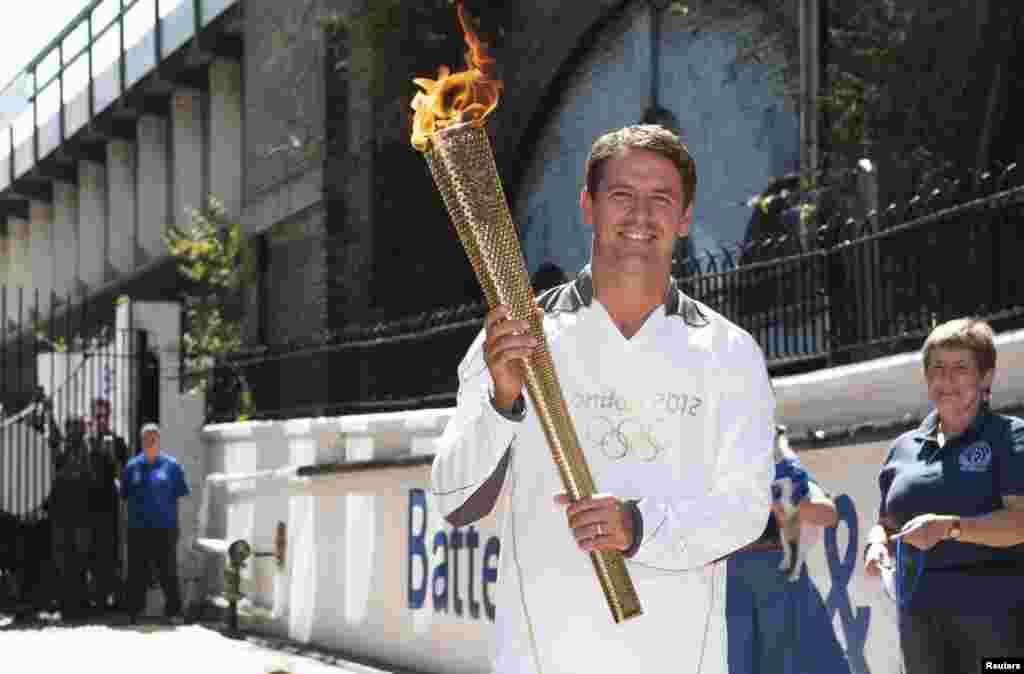 Former England striker Michael Owen poses with the Olympic Torch at Battersea dogs home in London, July 23, 2012. 