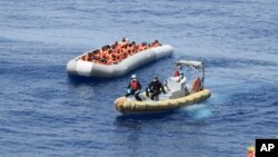 Des migrants en train d’être secourus en mer par la marine italienne. (Photo non datée, marine italienne via AP)