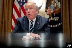 President Donald Trump speaks to reporters as he meets with members of Congress in the Cabinet Room of the White House, July 17, 2018, in Washington.