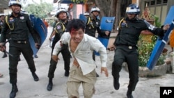 An injured Cambodian worker escapes from riot police in the compound of a Buddhist pagoda in Phnom Penh, Cambodia, Tuesday, Nov. 12, 2013. Cambodian police have fired live ammunition at protesting garment workers outside the capital, injuring at least six protesters and killing a bystander. The human rights group Licadho says hundreds of workers from the SL Garment Processing (Cambodia) Ltd. Factory clashed Tuesday with about 1,000 riot police sent to block a march from the factory to the Phnom Penh residence of Prime Minister Hun Sen. (AP Photo)