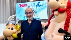 Penulis dan desainer Prancis Jean-Yves Ferri berpose di antara patung karakter buku komik Asterix dan Obelix saat presentasi album baru "Asterix" di rumah penerbitan Hachette Livre di Vanves, dekat Paris, 11 Oktober 2021. (Alain JOCARD / AFP)