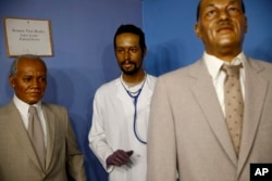 In this Aug. 15, 2018 photo, a wax figure depicting Department of Housing and Urban Development secretary Ben Carson, center, from his days as a neurosurgeon stands in a gallery at the National Great Blacks In Wax Museum in Baltimore.