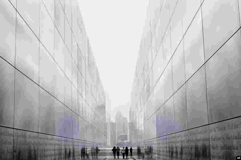 Tourists walk through the Empty Sky Memorial in Jersey City, NJ with the New York City skyline in the background on a overcast day in the New York area, March 10, 2019.