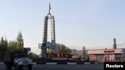 A truck drives past a sign at the entrance to the Kyrgyz city of Tokmok, April 20, 2013. 