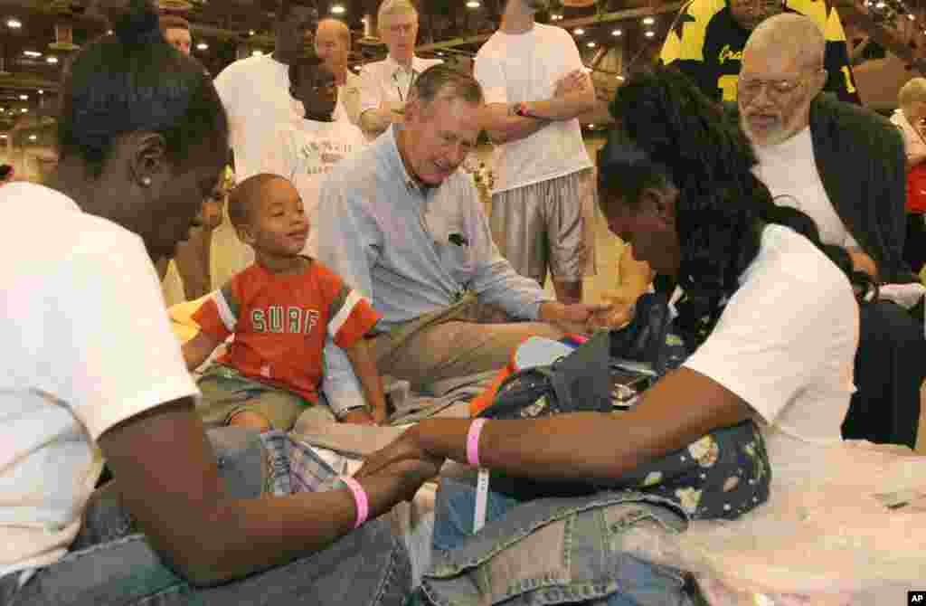 Former President George H.W. Bush prays with Hurricane Katrina evacuees Rebecca Solomon (left) Terrill Hoskins, 3, LaShonda Hoskins and Ernie Ladd in the Reliant Center adjacent to the Astrodome in Houston, Sept. 5, 2005.