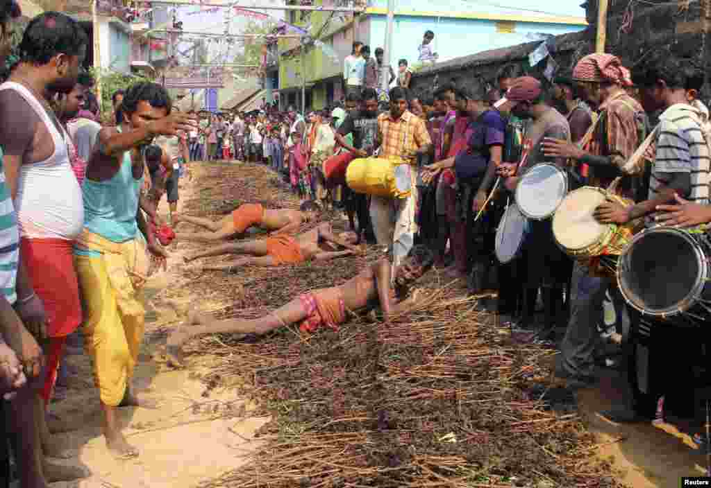 Devotees roll on thorny bushes laid on the ground to reach a temple as they perform a ritual during the "Danda" festival in Khurda district in the eastern Indian state of Odisha.
