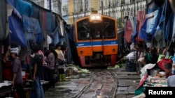 Thailand’s government wants to upgrade the national rail system. Venders pull back awnings and vegetables as a train arrives in Maeklong, in Samut Songkhram province, Aug. 16, 2012.