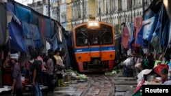 Thailand’s government wants to upgrade the national rail system. Venders pull back awnings and vegetables as a train arrives in Maeklong, in Samut Songkhram province, Aug. 16, 2012.