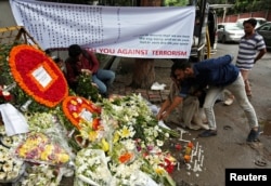 FILE - People place flowers at a makeshift memorial near the site, to pay tribute to the victims of the attack on the Holey Artisan Bakery and the O'Kitchen Restaurant, in Dhaka, Bangladesh, July 5, 2016.