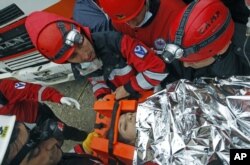 The surviving mother of a baby girl rescued from a collapsed building is taken to an ambulance in Ercis, near the eastern Turkish city of Van, October 25, 2011.