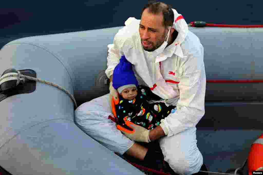 리비아 해안에서 난민 구조요원이 해안경비대에 의해 구출된 아기를 안고있다.