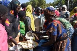FILE - Cameroonians who fled deadly intercommunal violence between Arab Choa herders and Mousgoum and Massa farming communities receive food at a temporarily refugee camp on the outskirts of Ndjamena, Chad, Dec. 13, 2021.