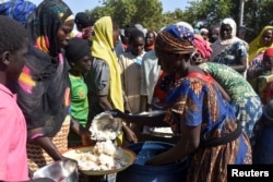 FILE - Cameroonians fleeing deadly inter-sectarian violence between Arab Choa herders and the Moosegoum and Massa farming communities receive food at a makeshift refugee camp on the outskirts of Nedjamena, Chad, December 13, 2021.