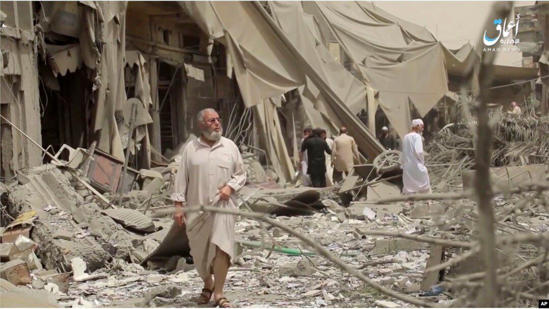 This undated frame grab from video posted online May 29, 2017, by the Aamaq News Agency, a media arm of the Islamic State group, shows people inspecting damage from airstrikes and artillery shelling in the northern Syrian city of Raqqa.
