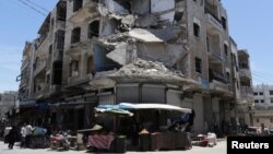 People walk past a damaged building in the city of Idlib, Syria, May 25, 2019.