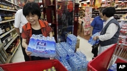 Customers stock cartons of bottled water at a supermarket in Hangzhou, Zhejiang province, after a local river, which is the source of drinking water, was polluted by a chemical leakage, June 6, 2011.