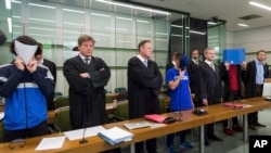 Three of the six young men accused of joint attempted murder in an attack on a homeless person hide their faces as they stand with their lawyers in the regional court in Berlin, Germany, June 13, 2017. 