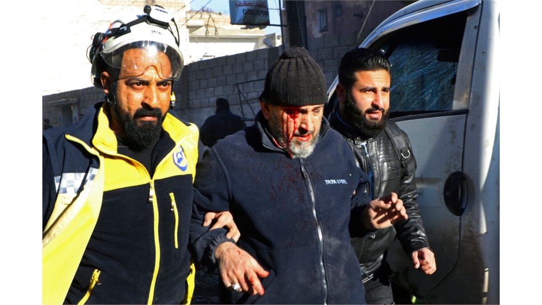 This photo provided by the Syrian Civil Defense White Helmets, which has been authenticated based on its contents, shows a Syrian White Helmet civil defense worker, left, helping an injured man, in the town of Afrin, north of Aleppo, Jan. 20, 2022.