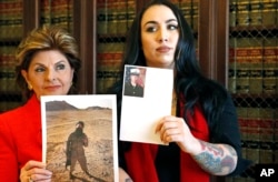 FILE - Former Marine Erika Butner, right, stands with attorney Gloria Allred holding photos of Butner in uniform as she and another active-duty female Marine said photographs of them were secretly posted online without their consent, at a news conference in August 2016.