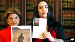 Former Marine Erika Butner, right, stands with attorney Gloria Allred holding photos of Butner in uniform as she and another active-duty female Marine said photographs of them were secretly posted online without their consent, at a news conference in Los Angeles, March 8, 2017.